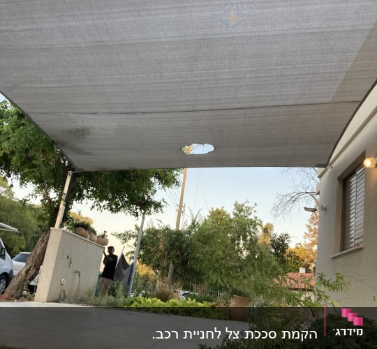 סוכך אפור מותקן בחצר עם צמחייה מסביב